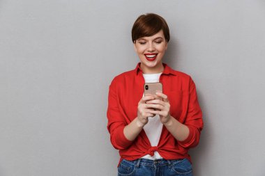 Gülümseyen ve cep telefonu tutan çekici bir genç kadın resmi