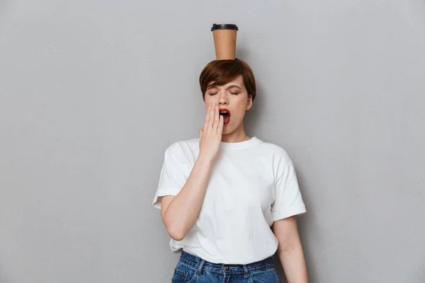 Image of sleepy woman yawning with takeaway coffee cup on her he — Stockfoto