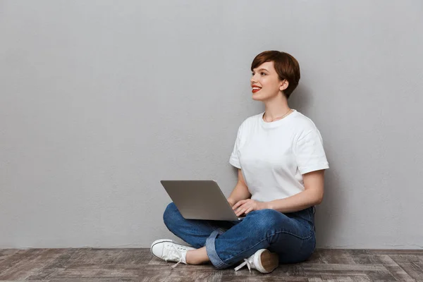 Immagine di donna soddisfatta seduta sul pavimento e utilizzando computer portatile di calcolo — Foto Stock