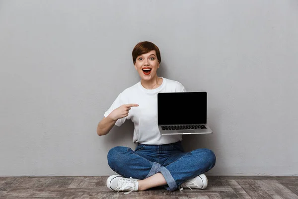 Imagen de la mujer emocionada mostrando la pantalla del ordenador portátil mientras está sentado en fl — Foto de Stock