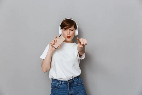 Image of cheerful young woman singing with headphones and smartp — Stock Photo, Image