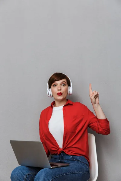 Image of surprised woman in headphones sitting on chair with lap — Stok fotoğraf