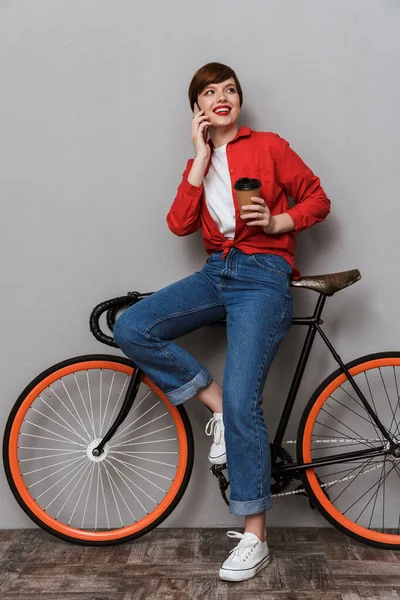 Pełna długość obrazu szczęśliwej kobiety mówiącej na smartfonie przez bicycl — Zdjęcie stockowe
