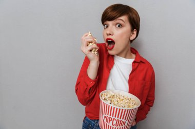 Elinde kağıt kova tutan ve patlamış mısır yiyen şaşırmış bir kadın resmi