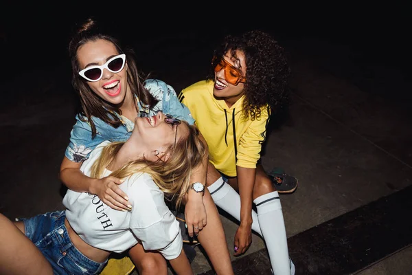 Beeld van gelukkige multinationale meisjes die glimlachen en op skateb zitten — Stockfoto