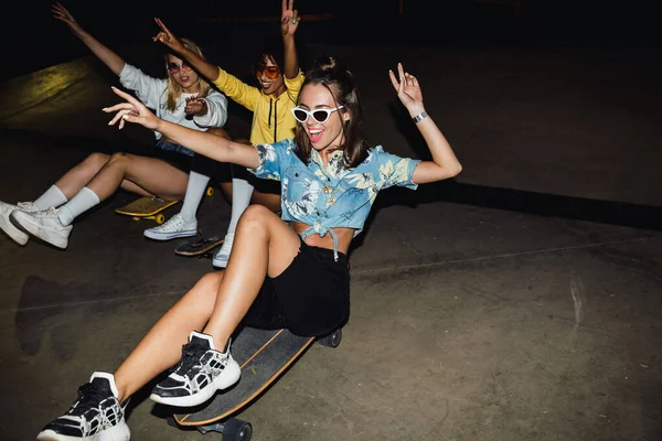 Beeld van glamour multinational girls riding on skateboards at ni — Stockfoto