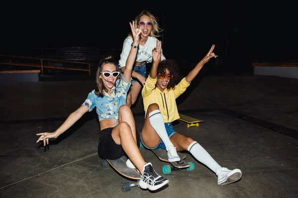 Image of three multinational girls smiling and riding on skatebo — Stockfoto