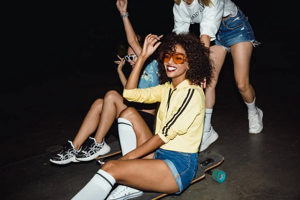 Image of teenage multinational girls riding on skateboards at ni — Stock Photo, Image