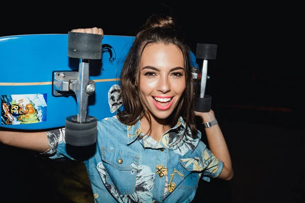 Immagine della giovane ragazza caucasica che sorride e tiene lo skateboard a — Foto Stock