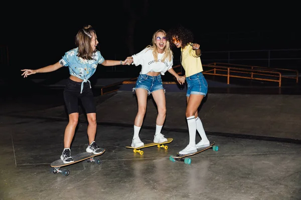 Imagen de chicas multinacionales felices sonriendo y montando monopatín — Foto de Stock