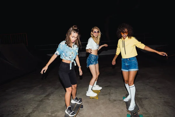 Imagem de meninas multinacionais adolescentes sorrindo e andando de skateboa — Fotografia de Stock