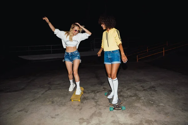 멋진 두 소녀가니 그 에서웃고 스케이트 보드를 타는 모습 — 스톡 사진