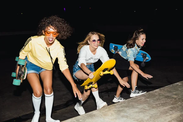 Imagem de sedutoras meninas multinacionais sorrindo e andar de skatebo — Fotografia de Stock