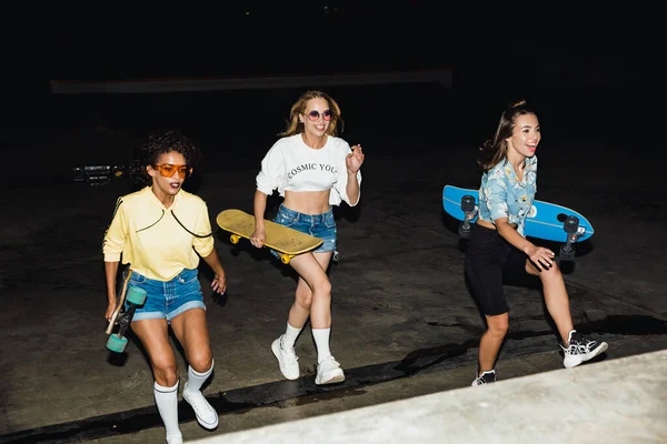 Image of fashion multiethnic girls smiling and riding skateboard — Stock Photo, Image