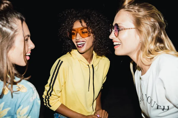 Beeld van gelukkige multi-etnische meisjes glimlachen en wandelen 's nachts ou — Stockfoto