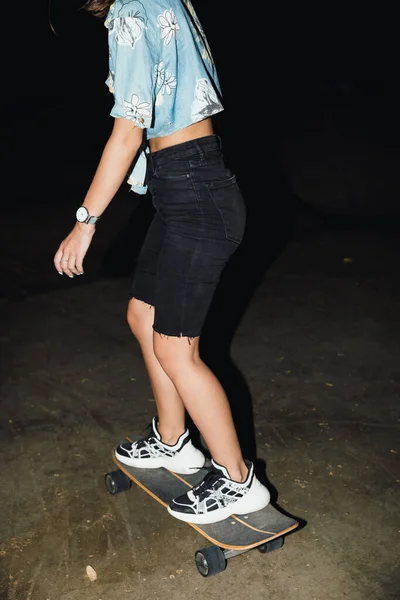 Frau läuft nachts auf Skateboard durch die Straße. — Stockfoto