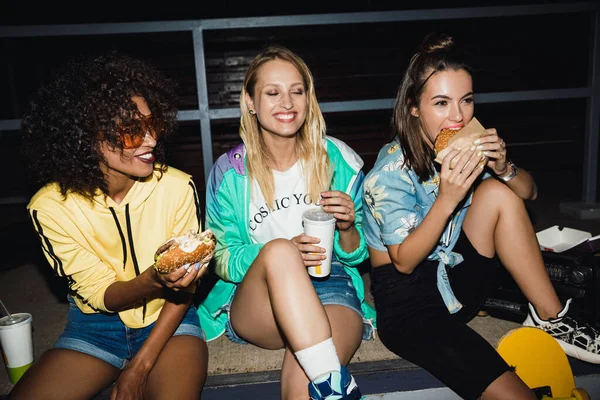 Зображення багатоетнічних дівчат, які їдять фастфуд і питну соду в — стокове фото