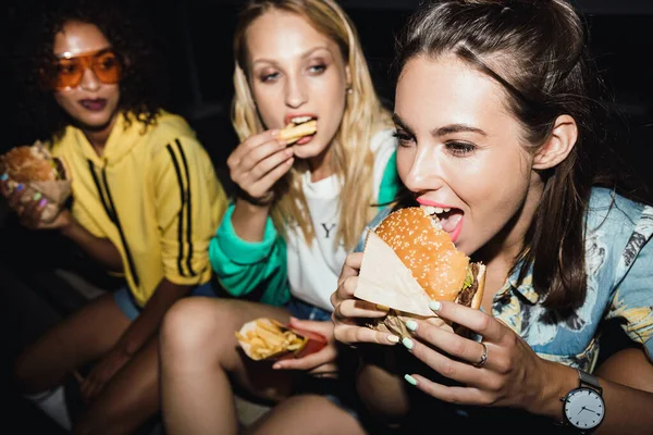 Imagen de chicas multiétnicas comiendo comida rápida y bebiendo refrescos en —  Fotos de Stock