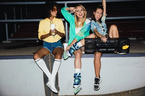 Imagem de meninas alegres sentadas com skate e boombox em n — Fotografia de Stock