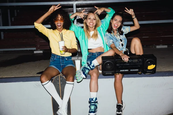 Bild av glada flickor som sitter med skateboard och boombox spelare — Stockfoto