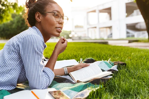 Immagine di una bella donna afroamericana che legge un libro nel parco — Foto Stock