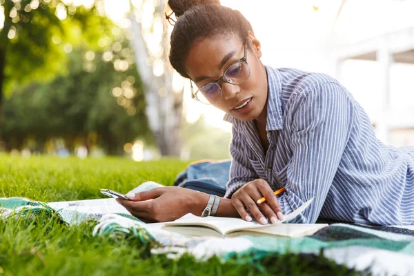 Bild av smart afrikansk amerikansk kvinna som studerar i parken — Stockfoto