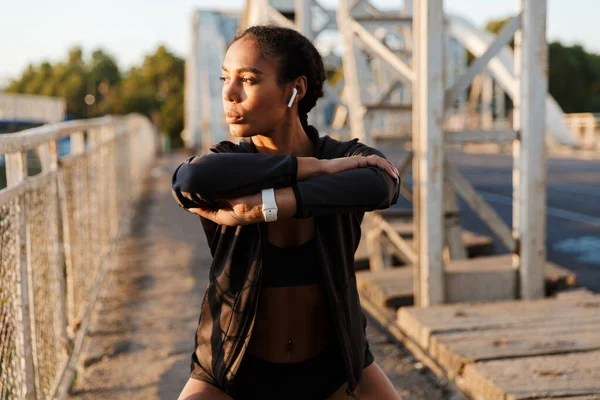 Photo of african american woman using earpods and doing exercises — Stock Photo, Image