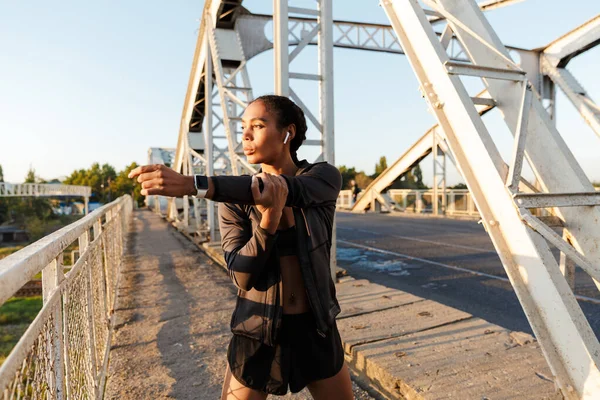 Photo d'une femme afro-américaine utilisant des écouteurs et faisant des exercices — Photo