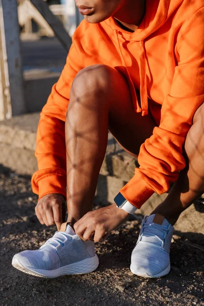 Cropped photo of african american woman tying shoelaces while sitting — Stock Photo, Image