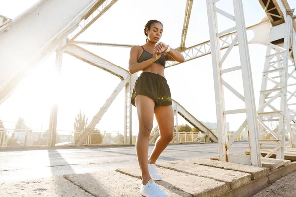 Fotografie de african american femeie frumoasă folosind smartwatch în timp ce lucra afară — Fotografie, imagine de stoc