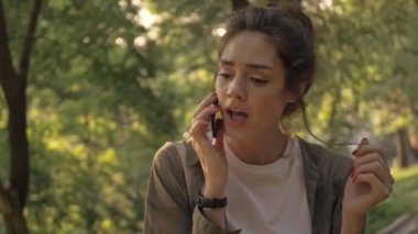 Parkta yürürken gülümseyen ve konuşan çekici esmer kadın.