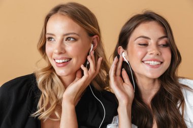 Kulaklıkla müzik dinleyen iki neşeli kadının portresi.