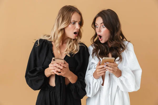 Portret van twee geschokte mooie vrouwen met smartphones — Stockfoto