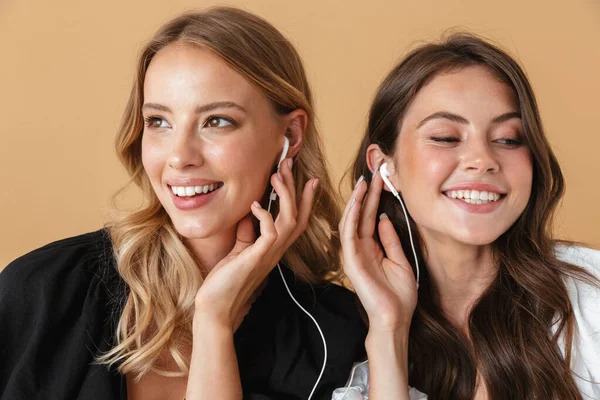 Retrato primer plano de dos mujeres alegres escuchando música con auriculares —  Fotos de Stock