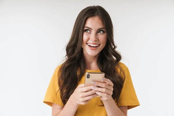 Optimistic soñando joven mujer emocional posando aislado sobre fondo de pared blanca utilizando el teléfono móvil . — Foto de Stock