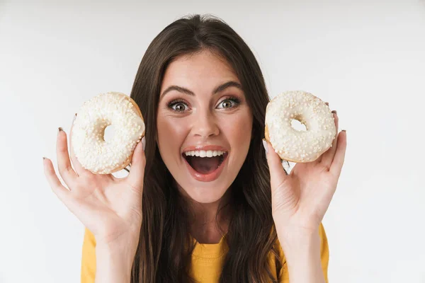 Positive glückliche junge Frau posiert isoliert über weißen Wand Hintergrund halten Donuts Süßigkeiten. — Stockfoto