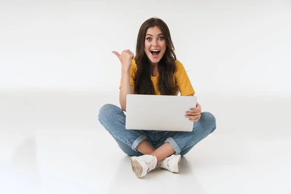 Emocional surpreendido alegre jovem mulher isolada sobre fundo da parede branca usando computador portátil apontando . — Fotografia de Stock