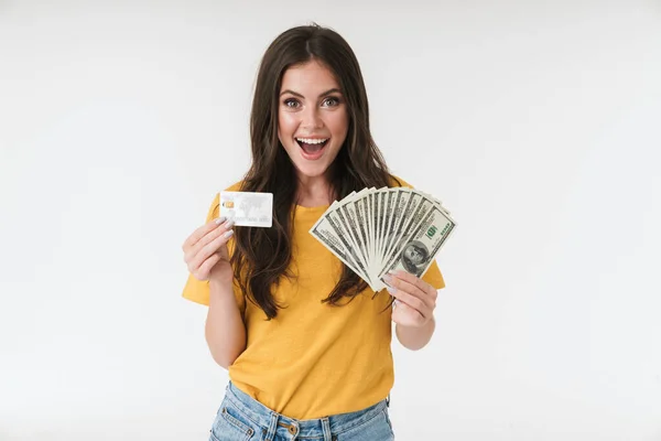 Feliz alegre jovem positivo isolado sobre fundo parede branca segurando dinheiro e cartão de crédito . — Fotografia de Stock