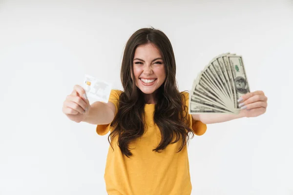 Szczęśliwy wesoły pozytywny młoda dziewczyna izolowane nad białą ścianą tła trzyma pieniądze i karty kredytowe. — Zdjęcie stockowe