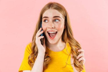Happy emotional cute girl isolated over pink wall background talking by mobile phone.