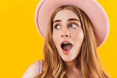 Sarı duvar arkasında ağzı açık şapkası olan yalnız bir kız..