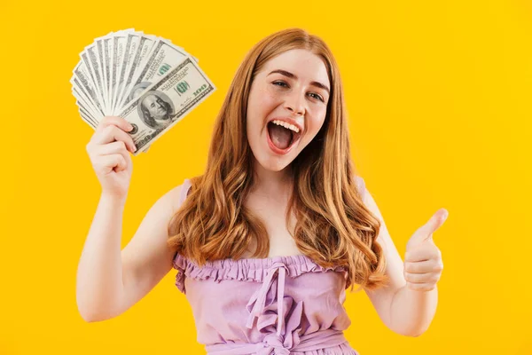 Joven chica feliz positivo aislado sobre fondo de la pared amarilla celebración de dinero mostrando los pulgares hacia arriba gesto . —  Fotos de Stock