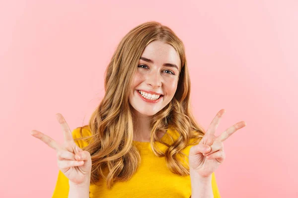Šťastný veselý optimistický roztomilý dívka izolované přes růžové stěny pozadí ukazující mír gesto. — Stock fotografie