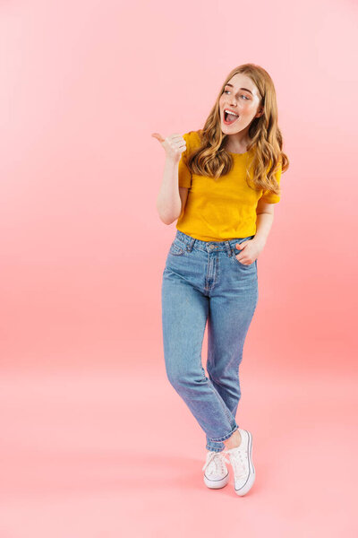 Positive emotional cute girl isolated over pink wall background showing copyspace.