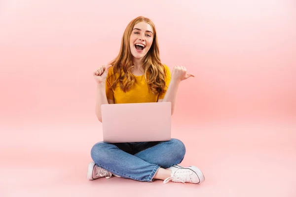 Emocional sonriente chica alegre aislado sobre fondo de pared rosa utilizando ordenador portátil que muestra cpyspace . — Foto de Stock