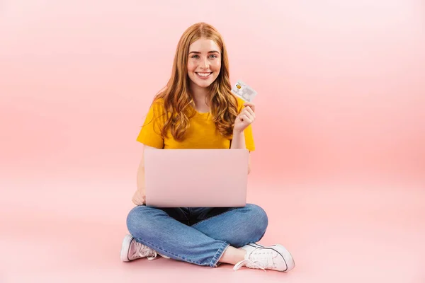 Chica alegre sonriente positiva aislado sobre fondo de pared rosa utilizando ordenador portátil . —  Fotos de Stock