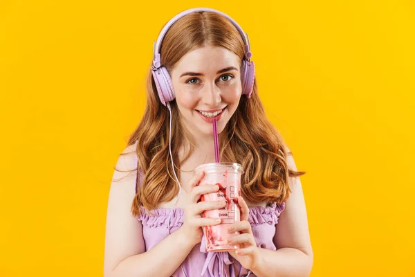 노란 벽을 지나서 이어폰으로 음악을 듣고 있는 행복 한 소녀. — 스톡 사진