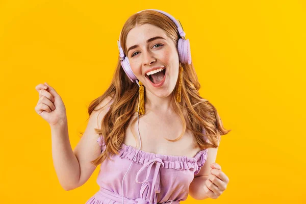 Menina feliz isolado sobre fundo de parede amarela ouvir música com fones de ouvido . — Fotografia de Stock