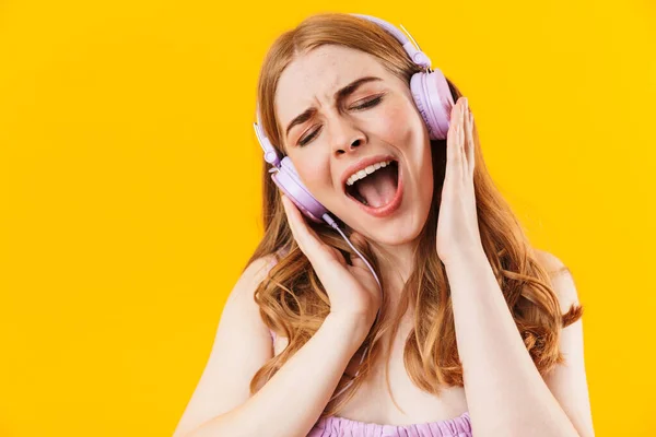 Menina feliz isolado sobre fundo de parede amarela ouvir música com fones de ouvido . — Fotografia de Stock