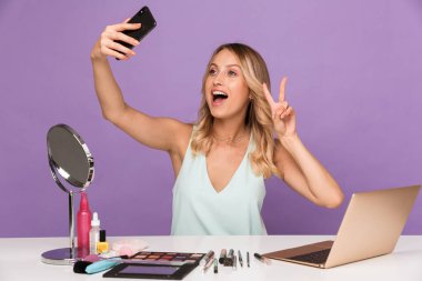 Barış şarkıları söylerken cep telefonunda selfie çeken komik bir kadın görüntüsü.